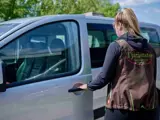 Een begeleider stapt in een auto