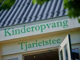 Een schuine opname van de tekst ‘Kinderopvang Tjariestee’ bovenop een deur