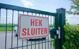 Een bord op een hek met de tekst “Hek Sluiten”.