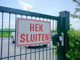 Een bord op een hek met de tekst “Hek Sluiten”.