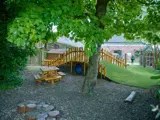 Een boom met een picknicktafel ernaast bij de speeltuin